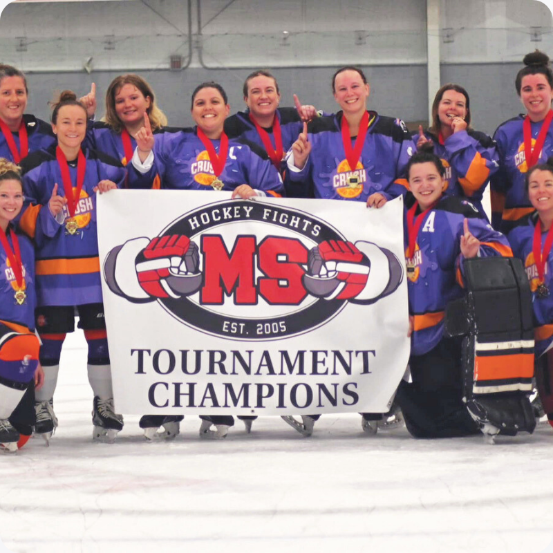 A women's hockey team with custom Jerseys Made Easy jerseys posing on the ice of a community hockey rink.