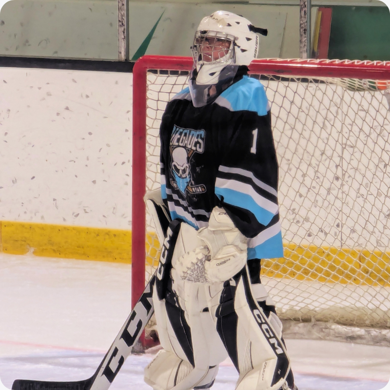 A hockey goalie on the ice in full hockey gear wearing a custom Jerseys Made Easy hockey jersey.