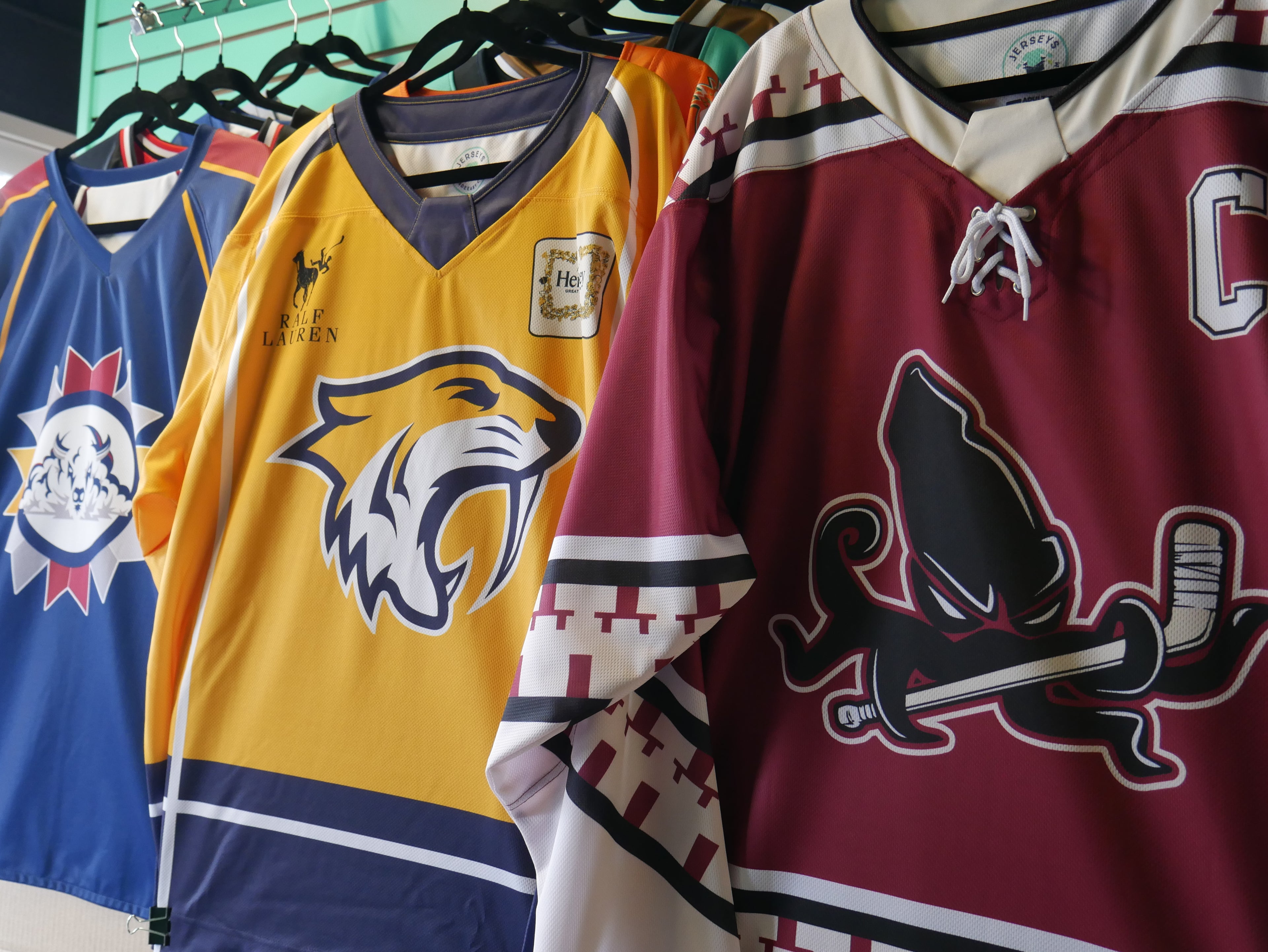 Sublimated hockey jersey examples hanging in our Kitchener, Ontario showroom for visitors to browse, touch, and feel.